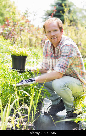 Portrait en pied de l'homme heureux holding potted plant au jardin Banque D'Images