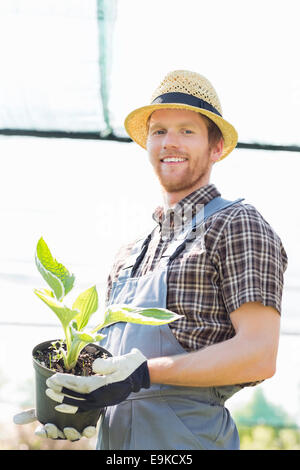 Portrait of happy gardener holding potted plant à émissions de Banque D'Images