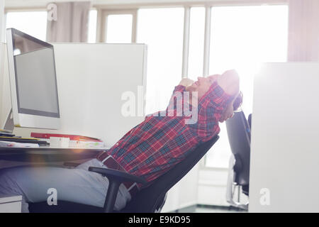 Side view of young businessman relaxing at desk in office Banque D'Images