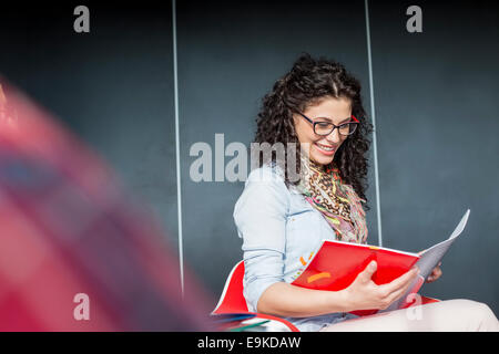 Happy businesswoman reading book in office Banque D'Images