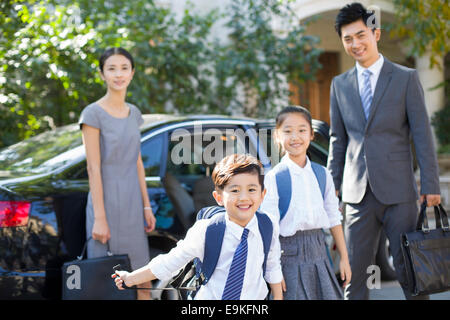 Jeune couple portant leurs enfants de l'école Banque D'Images