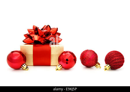 Gold Christmas gift box avec arc rouge et décorations babiole rouge sur fond blanc Banque D'Images