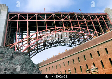 La face inférieure du Golden Gate Bridge avec des poutres en acier rouge complexes surplombant les murs de briques historiques de Fort point à San Francisco. Banque D'Images
