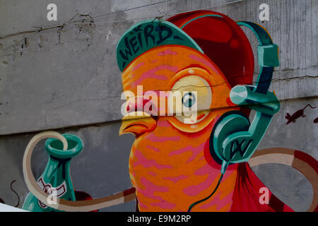 Street art Graffiti Mur de Berlin avec un casque d'oiseaux cartoon color Banque D'Images