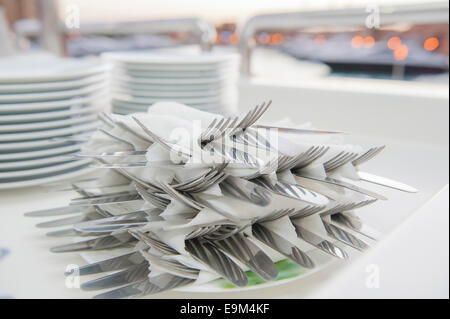 Pile de couteaux et fourchettes couverts enveloppés dans des serviettes sur une plaque Banque D'Images