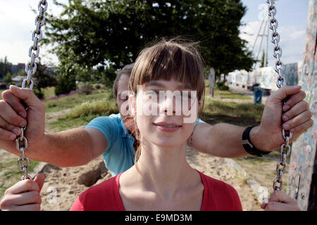 Man pushing woman on swing aire