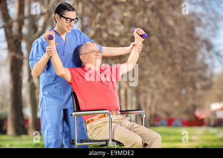 Physiothérapeute l'entraînement avec un patient mature in park Banque D'Images