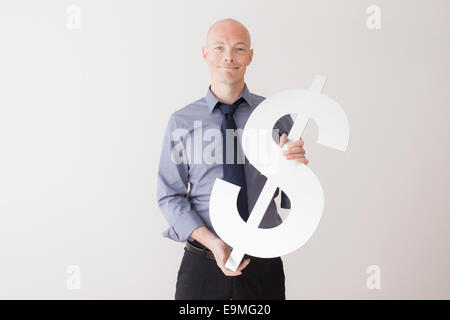 Portrait of businessman holding dollar sign against white background Banque D'Images