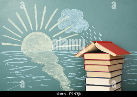 Concept de l'éducation inhabituels. L'École de livres sur fond de dessin à la craie de soleil et de pluie. Banque D'Images