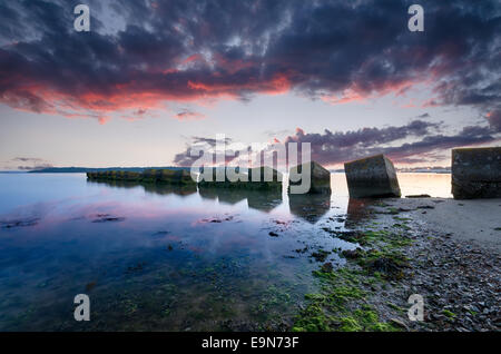 Un lever de soleil sur les cubes de béton, ancien WWII tank défense Studland beach dans le Dorset Banque D'Images