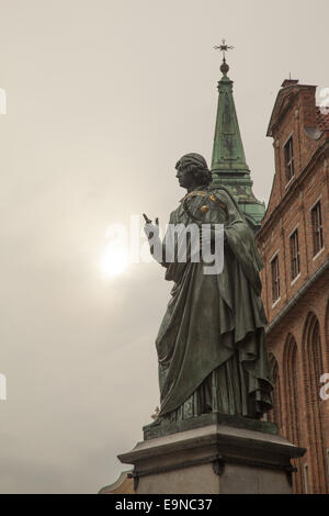 Monument à Copernic avec le soleil et clocher de l'église derrière. Torun, Pologne Banque D'Images