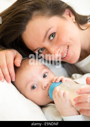 L'alimentation de la mère enfant garçon avec une bouteille de lait à la maison Banque D'Images