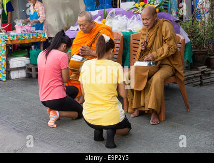 Bangkok, 29 Thailand-September 2014 : deux femmes s'agenouiller devant deux moines afin de rendre le mérite à Bangkok, Thaïlande. Ce composé Banque D'Images