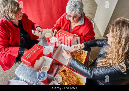 Trois générations de femmes prêts à manger du poisson et frites, assis à une table, en dehors de Harry Ramsdens à côté de la plage de Bournemouth, Dorset, England, UK. Banque D'Images