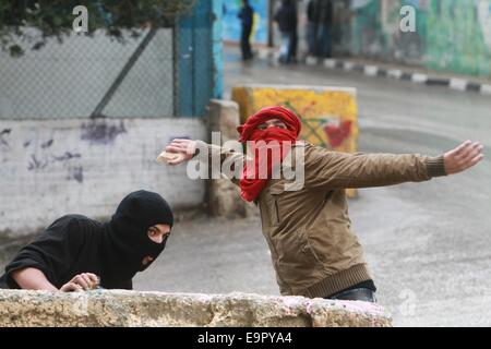 Bethléem. 31 octobre, 2014. Un manifestant palestinien lance des pierres en direction des soldats israéliens lors d'affrontements dans le camp de réfugiés de Aida dans la ville cisjordanienne de Bethléem le 31 octobre 2014. Des heurts ont éclaté vendredi entre manifestants palestiniens et soldats israéliens dans plusieurs villes de Cisjordanie. Credit : Luay Sababa/Xinhua/Alamy Live News Banque D'Images