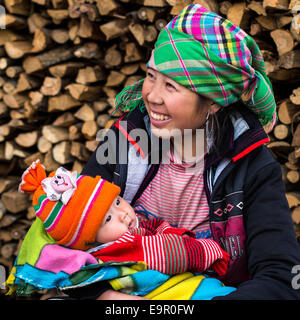 Femme Hmong heureux avec bébé, souriant, assis dehors au village Ta Van près de Sapa, province de Lao Cai, Vietnam du Nord. Banque D'Images