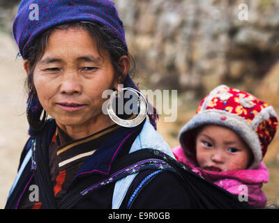 Femme Hmong portant des costumes traditionnels et de bijoux et de port d'enfant non identifiés dans la ville de Sapa, Vietnam du Nord. Banque D'Images