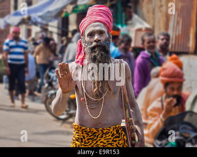 Portrait d'un sadhu indien (saint homme) recouvert de cendres et de porter des vêtements de couleur vive dans une rue animée de Varanasi, en Inde. Banque D'Images