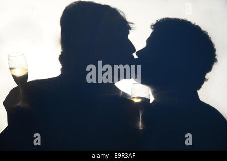 Silhouette d'hommes gay s'embrasser le jour de leur mariage, holding derrière un écran opaque. Banque D'Images
