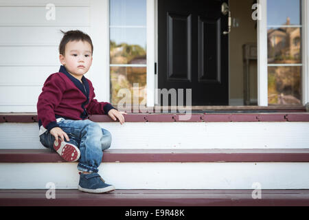 Mélancolie Cute Boy assis sur les marches de la véranda avant. Banque D'Images