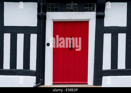 Porte avant rouge dans un cadre en bois traditionnel anglais Tudor house Banque D'Images