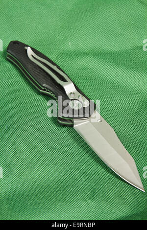 Couteau pliant avec un manche noir et serrure sur toile verte Banque D'Images