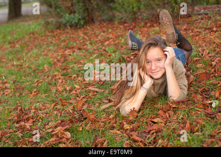 Cute teen girl lying on ground automne jaune avec les feuilles qui tombent. Banque D'Images