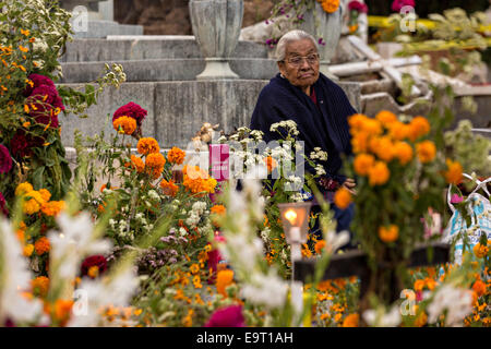 Une femme âgée reflète à la tombe de son défunt mari au cimetière Xoxocatian décorées avec des fleurs et des bougies pour le jour de la Fête des Morts connus en espagnol comme d'un de muertos le 31 octobre 2014 à Oaxaca, au Mexique. Banque D'Images