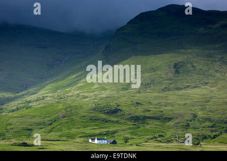 Petit solitaire blanc croft ferme nichée au-dessous de montagnes par loch sous moody sky sur l'île de Mull dans les Hébrides intérieures Banque D'Images