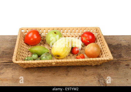 Mûr et ONU-tomates mûres et de concombre dans un panier sur une planche en bois Banque D'Images