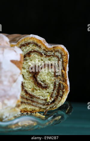 Doux gâteau levure Noël produites rempli de caroubiers et de cannelle (Potica) cerise sur le gâteau en verre et support en bois turquoise bac Banque D'Images