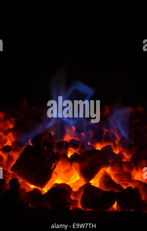 Chaud rougeoyant de braises rouges (charbon) et bleu en flammes cheminée Banque D'Images