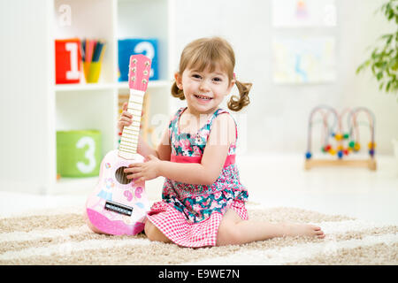 Petite fille aux cadeaux jouet guitare Banque D'Images