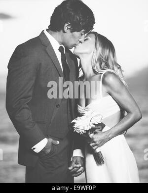 Beau couple de mariage, mariée et le Marié baiser sur la plage au coucher du soleil. Photographie noir et blanc Banque D'Images