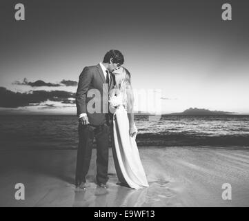 Beau couple de mariage, mariée et le Marié baiser sur la plage au coucher du soleil. Photographie noir et blanc Banque D'Images