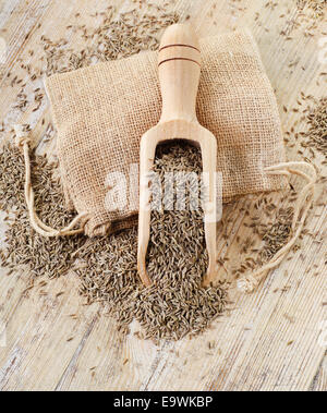 Les graines de cumin dans scoop en bois sur une table en bois Banque D'Images
