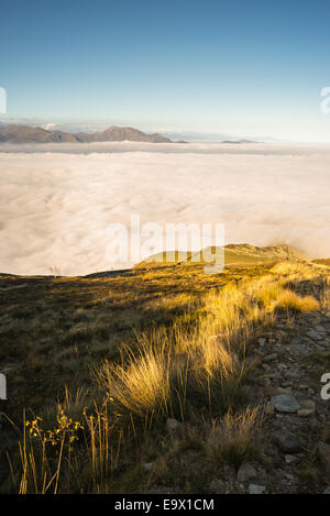 Paysage magnifique au coucher du soleil sur les Alpes occidentales italiennes de nuages couvrant la vallée ci-dessous. Banque D'Images