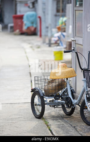 Tricycle avec un petit chapeau de paille chinois dans une ruelle étroite à Tai O, Lantau Island, Hong Kong. Banque D'Images