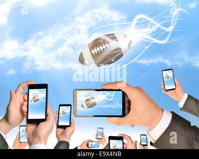 Mains tenant des téléphones intelligents et des vidéos comme relevant de football américain Banque D'Images