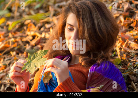 Portrait de jeune femme en automne, à la recherche d'une feuille, tourné en plein air Banque D'Images