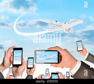 Mains tenant des téléphones intelligents et des vidéos comme flying airplane Banque D'Images