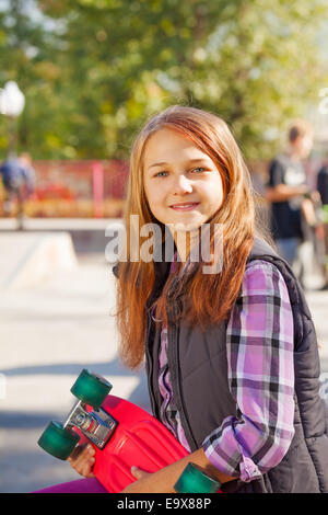 Cute smiling girl with long hair et skateboard Banque D'Images