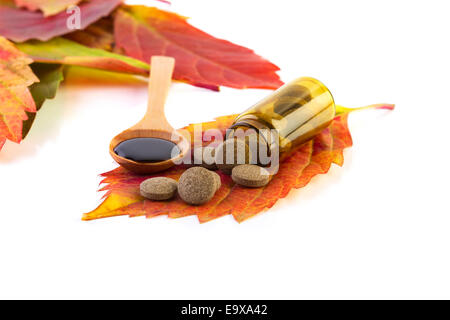 Flacon de médicaments, pilules sur feuille et d'érable de cuillère en bois sur fond blanc Banque D'Images