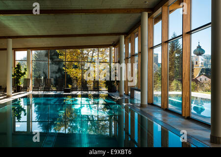 Vue d'une piscine intérieure et extérieure d'un hôtel avec des réflexions et un clocher dans le lointain à l'automne Banque D'Images