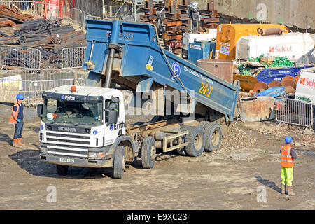 Ouvriers à côté de camion benne basculante hgv bennage matériaux de remplissage rigide sur le site de construction de fondation de sous-sol encombré Londres Angleterre Royaume-Uni Banque D'Images