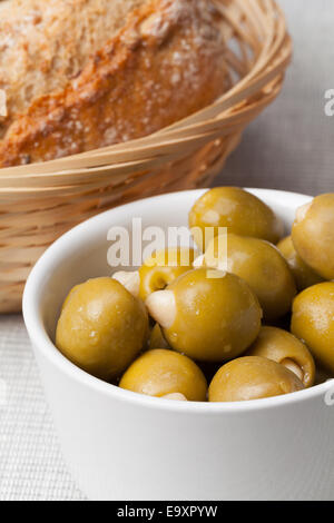 Un bol d'olives vertes farcies aux amandes. Pain fait maison servi dans un osier. Banque D'Images