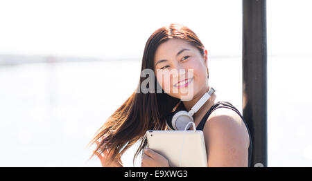 Une jeune femme asiatique en utilisant sa tablette alors qu'elle est dehors et environ en milieu urbain Banque D'Images