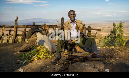 Homme en costume africain vend du maïs à l'Kamandura Mai-Mahiu Narok route près de la Grande Vallée du Rift au Kenya Banque D'Images