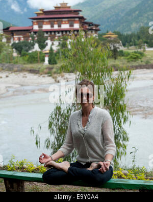 Femme méditant avec le Monastère de Punakha en arrière-plan, Punakha, Bhoutan Banque D'Images