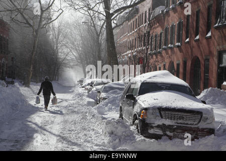 Homme portant des sacs de shopping lors d'une forte tempête de neige à Brooklyn New York Banque D'Images